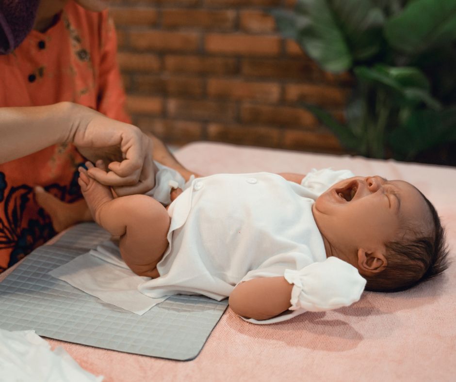 Baby getting nappy changed on a changing table.